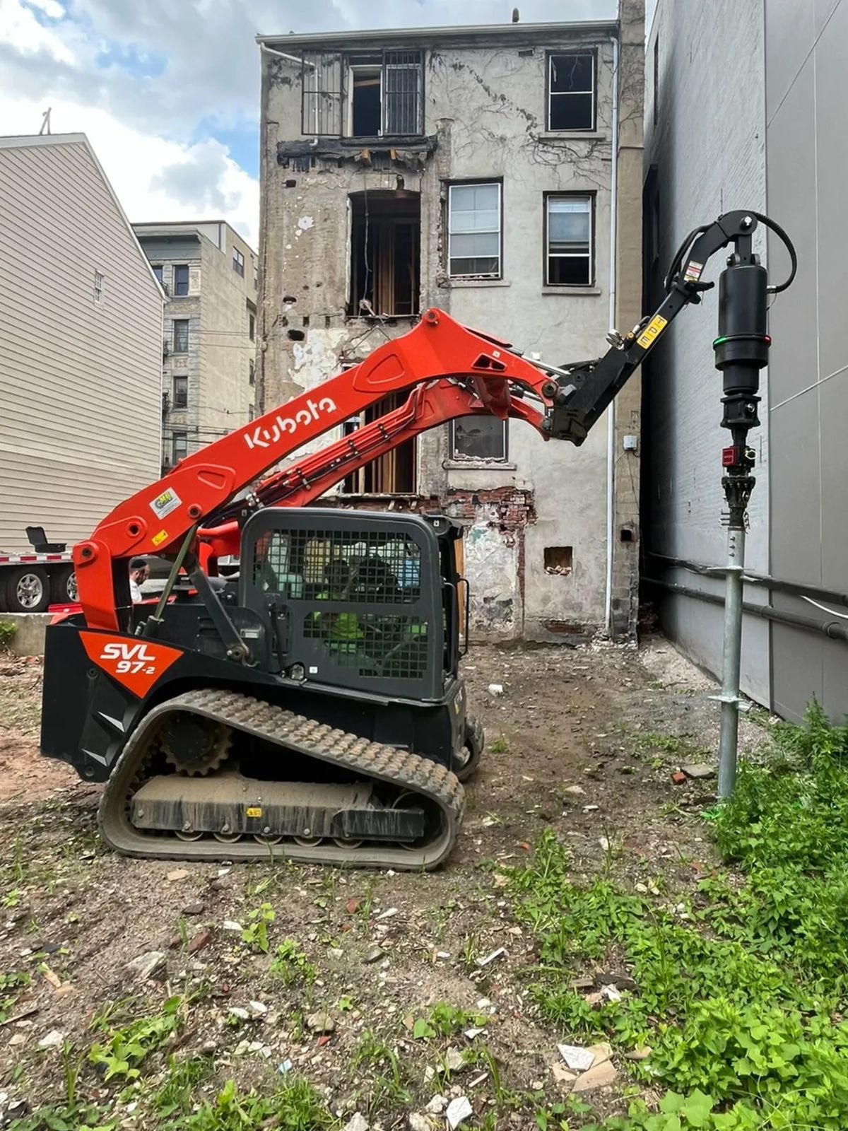 Compact track machine driving a helical pile on a tight lot
